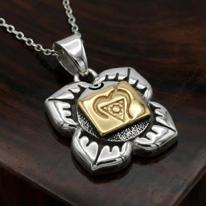 Chakra pendant for the Root Chakra at our pagan jewelry store resting at an angle on a rich, dark wood surface