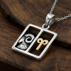 Aries pendant: Two-tone silver and gold horoscope necklace resting on a rich, dark wooden surface