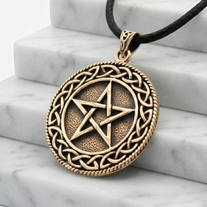 Gold Celtic pentacle draped gracefully across white marble steps at our witchy store, emphasizing the raised, polished points of the star against the solid textured bronze