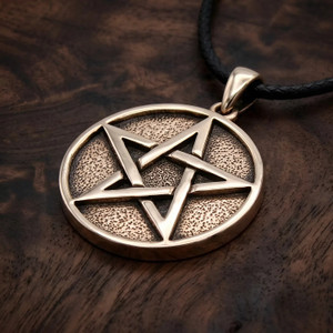 Witchcraft necklace at our witchy jewelry store resting flat on a rich dark wood grain surface, highlighting the polished interlocking star and dark stippled background
