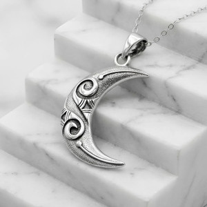 Large crescent moon pendant resting gracefully on white marble steps, a striking modern moon pendant necklace at our witch supply store