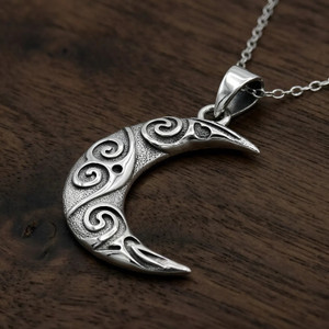 Oxidized moon necklace showcased on a rustic dark wood background, highlighting the antiqued patterns of this pendant at our Wicca supply store