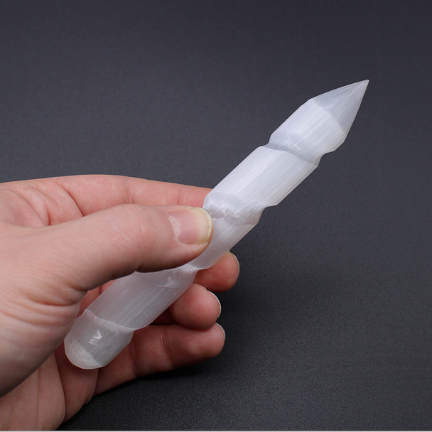Hand holding a glowing Selenite spiral wand for creating sacred circles and sacred spaces, removing energy blockages and casting spell work.