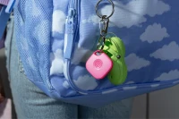 A Life360 Tile - Pink Punch attached to a blue sky backpack.
