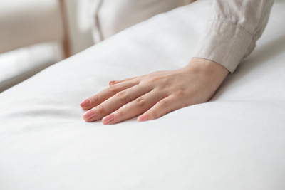 luxury bed sheets shown with woman admiring softness