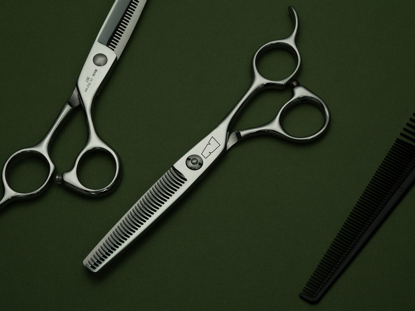 silver right handed scissors with black "N" logo and 35 teeth on one blade on a green background