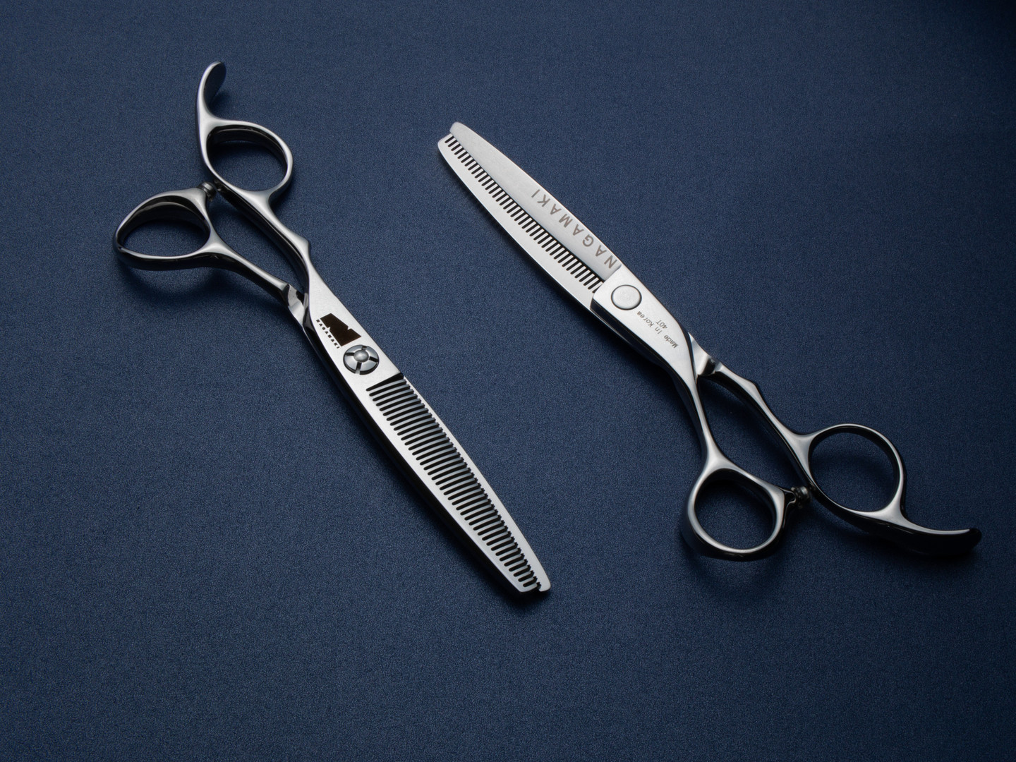silver left handed scissors with black "N" logo and 40 teeth on one blade on a blue background