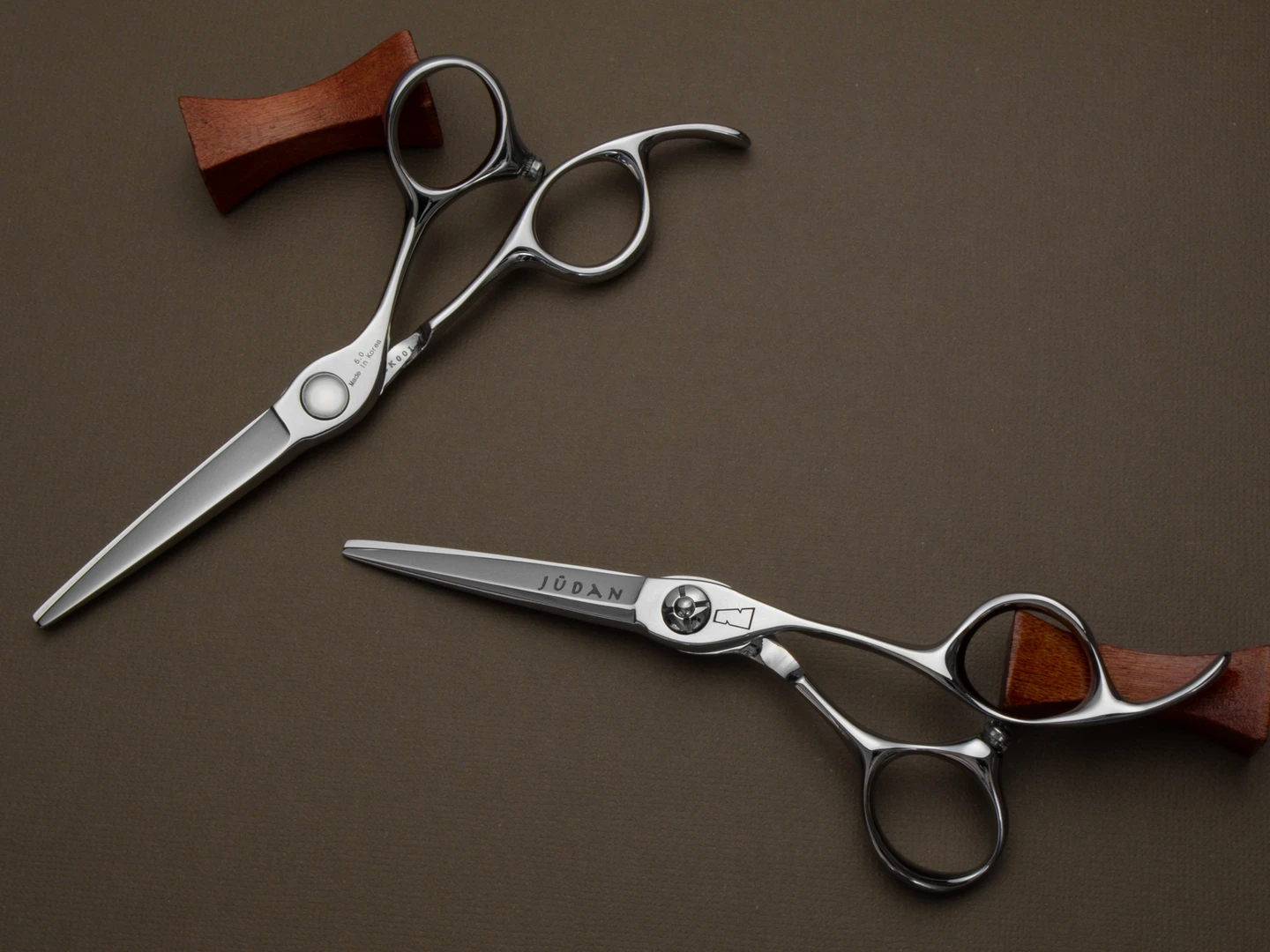 silver colored right handed hair scissor with black "N" logo and the word "judan' inscribed in black on the blade on a brown background