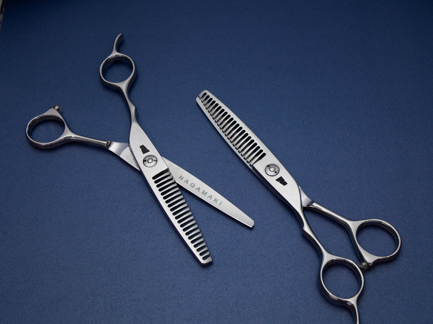 silver colored left handed hair scissor with black "N" logo with 21 teeth on one blade on a blue background