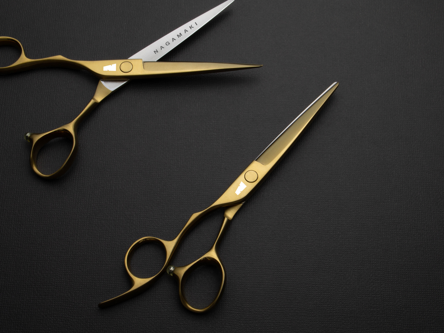 matte gold left handed hair scissor with white "N" logo on a dark background