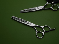 silver right handed scissors with black "N" logo and 26 teeth on one blade on a green background