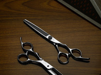 a silver right handed scissor with a "T" logo on the front and 35 teeth on one blade on a brown background.