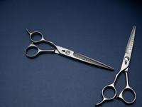 silver colored left handed hair scissor with black "N" logo against a blue background
