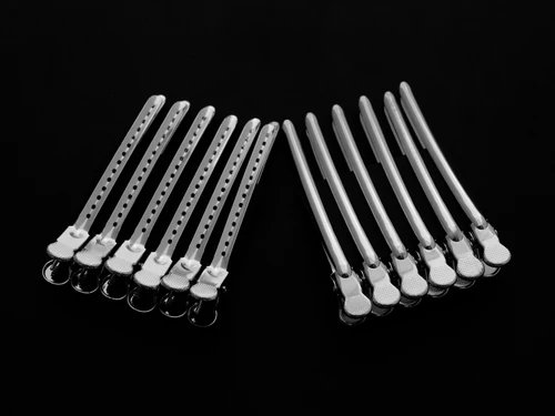 12 silver hair cutting clips on a black background