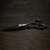 a silver right handed scissor with a black "N" logo laying flat on a dark background showing the blade curving downwards