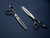 silver left handed scissors with black "N" logo and 40 teeth on one blade on a blue background