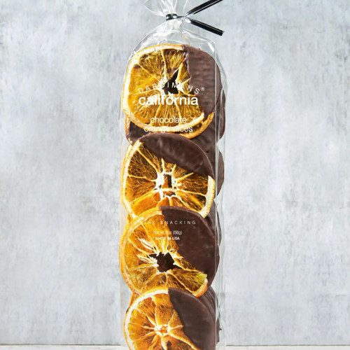 Crispy Orange Chocolate Slices - Elegant, dehydrated California orange slices half-dipped in a glossy layer of premium Belgian dark chocolate, arranged neatly in a clear protective tray within a sleek package. The vibrant orange hue contrasts beautifully with the dark chocolate for a visually striking, gourmet treat.