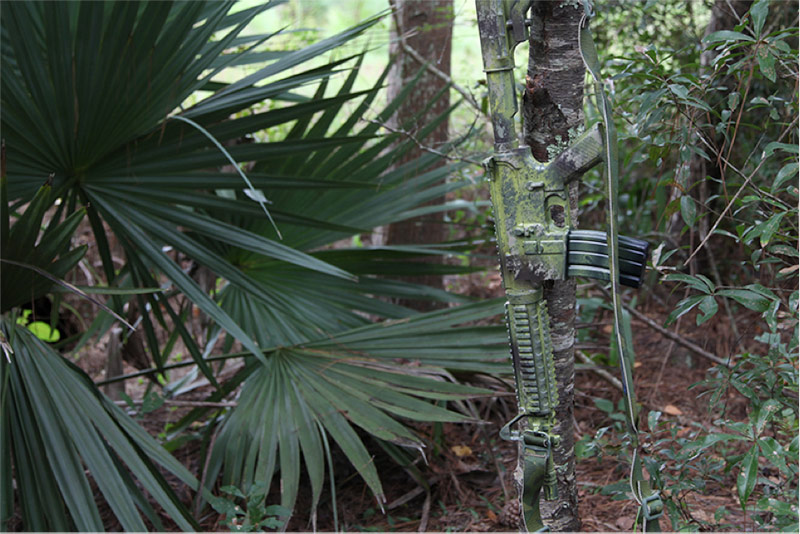 camo painted gun in forest