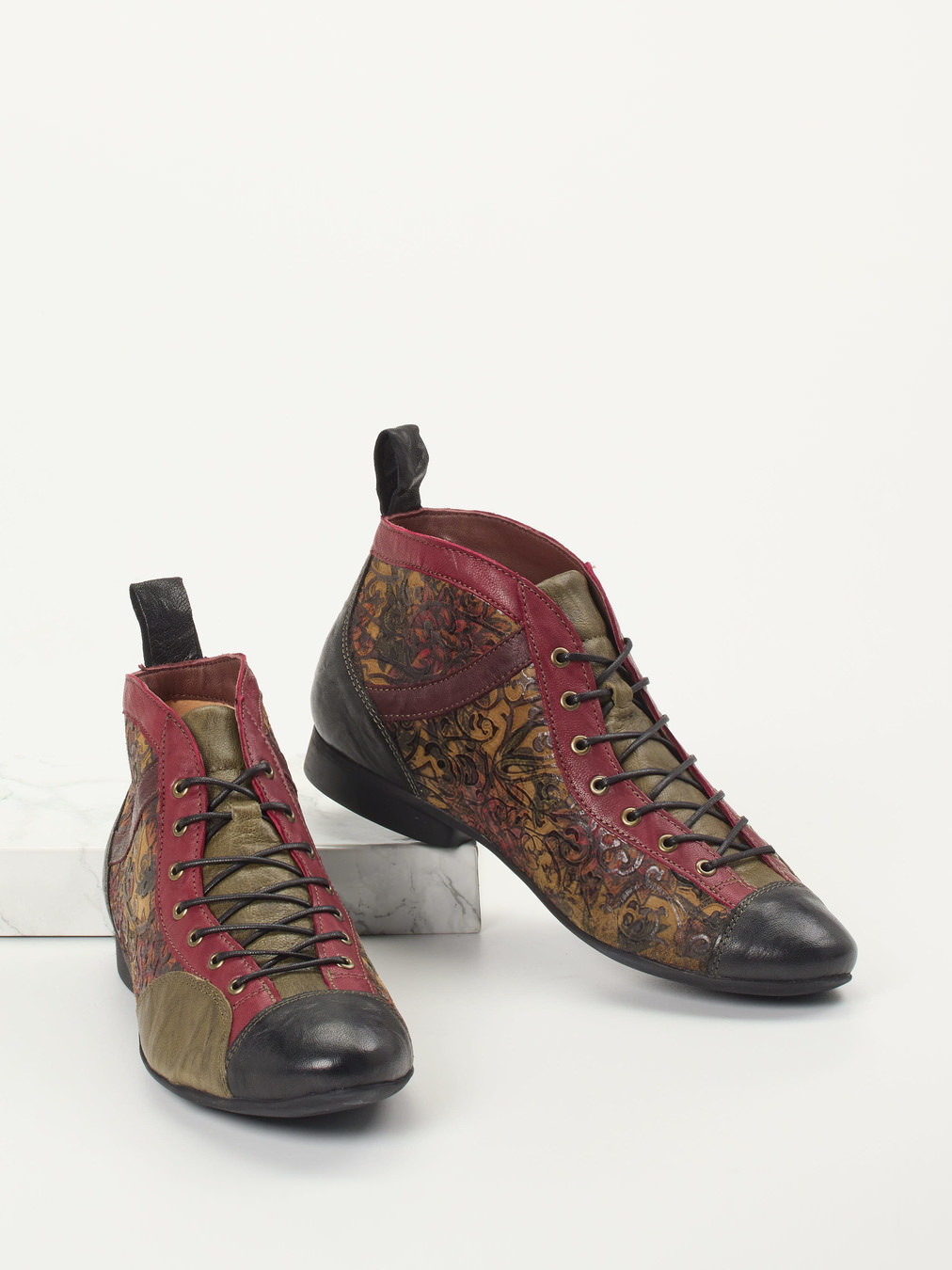 Die Firma Think steht für eine nachhaltige Produktion in Europa und echte Handwerkskunst. Hier stellt sie diese extravagante Schnürstiefelette in der Form Guad2 vor. Das geprägte Leder zeigt sich in rot und schwarz. Der Blickfang liegt jedoch auf dem fabelhaften Rankenmotiv. Die Schnürung im Zickzack-Stil ermöglicht eine passgenaue Weitenregulierung. Das bequem gepolsterte Fußbett kann bei Bedarf ausgetauscht werden. In der rutschfesten Gummisohle sind Luftpolster integriert, die stoßdämpfend wirken. multi 2751999001604