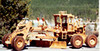 A view of the wooden Road grader displayed outside by shrubs.