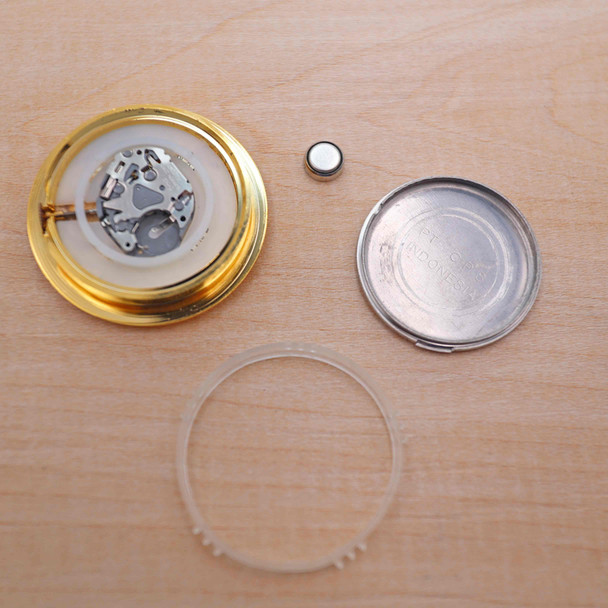 A mini clock insert showing the gears of the clock, clock case, battery, back cover and mounting gasket.
