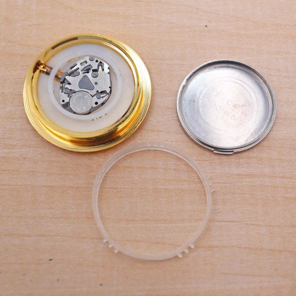 A mini clock insert with the back cover and gasket removed showing the clock works with the battery installed.