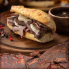 A life style shot of a sandwich on a wooden cutting board made with Peppery Au Jus Jerky seasoning.