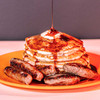 A lifestyle shot of Walton's Major Maple PSS with a stack of pancakes next to the sausage it was made with.