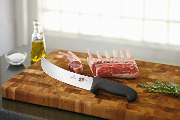 A 10" Cimeter Knife being used to cut ribs on a cutting board