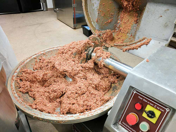 A close-up of meat being poured out of the 40 lb. Bowl Chopper