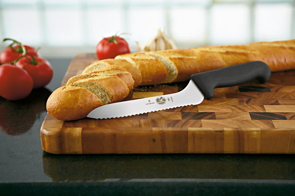 Wavy Bread Knife on display on a cutting board, with a loaf of sliced bread next to it