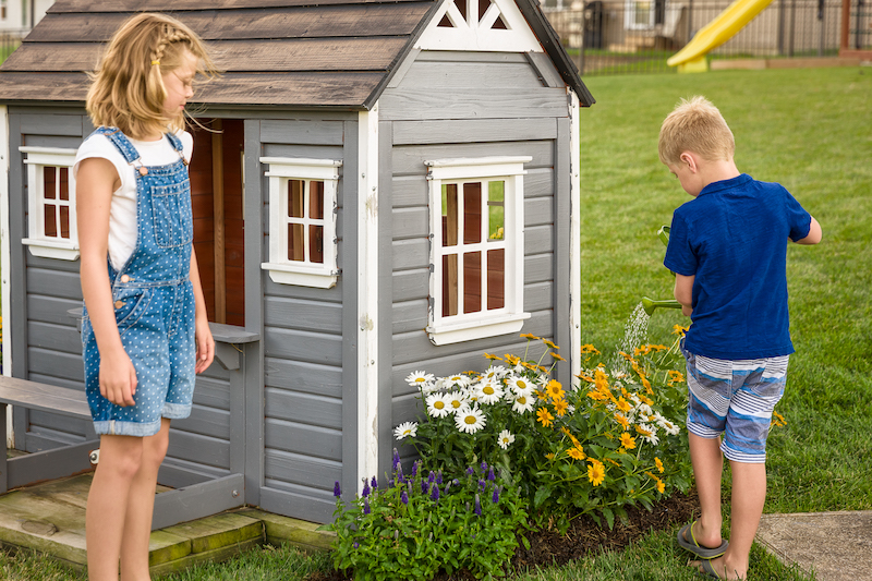 boy-watering-sunflowers-and-daisies-next-to-playhouse.jpg