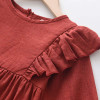 Generic Firebrick Ruffled Long Sleeve Romper Bodysuit, close-up of the rust-colored fabric with ruffle detail on the sleeve and neckline.