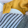Generic Giraffe Layette Set 4 Piece, a set of baby's clothing including a yellow knitted top, a gray and white striped outfit, and gray pants, arranged on a white surface.