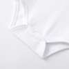 Minnie Me Cotton Romper Neutral, close-up image of the white textured cotton romper with snap buttons at the bottom for easy dressing.