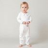 Minnie Me White Romper Christening Essential, a cute little girl wearing a white romper with a Peter Pan collar, holding a small plush leopard toy.