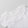 Minnie Me White Romper Cotton Essential, close-up of a white baby romper with ruffled collar and short sleeves made of soft cotton fabric.