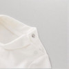 Minnie Me White Romper Cotton Essential, close-up of the white cotton romper's neckline and snap buttons on a neutral background.
