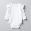 Minnie Me White Romper Cotton Essential, a white baby romper with ruffled sleeves and long sleeves, made of soft cotton fabric.