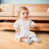Minnie Me Elie Formal Set with Short for Kids, baby girl sitting on the floor in a white short-sleeve outfit in front of a beige sofa.