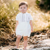 Minnie Me Elie Formal Set with short, a stylish white baby girl outfit, worn by a young child outdoors in natural sunlight.