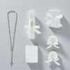 Minnie Me White 5 PCS Baptism Kit, image shows a white rosary with a cross, a white baptism candle decorated with lace and a bow, a small white gift box with a bow, and two white shell-shaped items decorated with bows for a baptism ceremony.