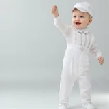 Minnie Me Liam Suspender Set, adorable baby boy wearing white suspender outfit with hat, celebrating and smiling.