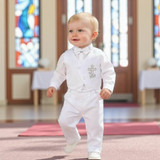 Minnie Me Little Lucas Christening Suit, a white formal suit for babies featuring a jacket with a cross embroidery on the chest, paired with matching trousers, suitable for a christening ceremony.
