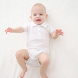 Minnie Me Cotton Romper Neutral, adorable baby smiling and lying down in a white romper.