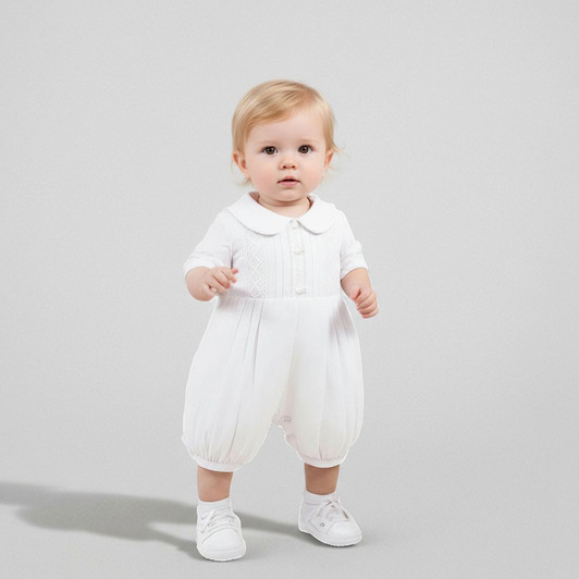 Minnie Me Mike White Baptism Romper, adorable baby girl in white baptism romper with collar, buttons, and elasticized cuffs, standing against a plain background.