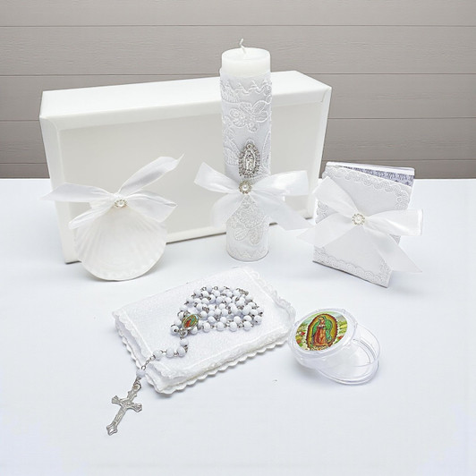 Minnie Me White 5 PCS Baptism Kit, religious baptism accessories including candle, rosary, prayer booklet, shell, and keepsake items arranged on a white surface with a white box in the background.