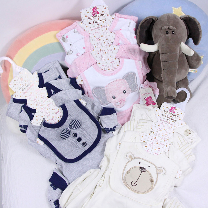 Generic Grey Cow 8-Piece Layette Set, collection of baby clothing and plush toy including grey and navy bibs, pink and white onesies with elephant design, plush elephant toy, and bear-themed pajamas for infants.