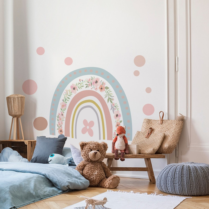 Generic Rainbow Wall Sticker Nursery Bedroom, a colorful rainbow wall decal with flowers and polka dots decorating the nursery wall behind children’s toys and cushions.