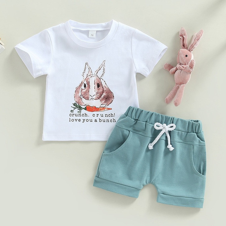 OONA 2PCS Easter Outfit Bunny Letter, toddler's white T-shirt with bunny face graphic and text, paired with mint green shorts with a white drawstring, and a pink bunny plush toy.